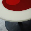 Particolare tavolo tondo diametro 120 cm. Struttura in ferro e piano d'appoggio in resina trasparente e colorata a strati.